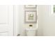 Clean, white toilet beneath modern artwork enhances the bathroom's minimalist aesthetic at 84 Blossom Field Way, Angier, NC 27501