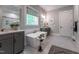 Bright bathroom with a soaking tub, dual vanity, decorative mirror, and a large window at 91 Ivy Ridge Rd, Chapel Hill, NC 27516