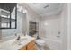 Bright bathroom with a single sink vanity, mirror, open shelving, and a shower and tub combo at 1003 Crimson Dr, Durham, NC 27713