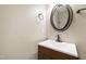 Powder room with wood cabinet, white sink, bronze faucet, and round mirror at 1005 Temple St, Raleigh, NC 27609