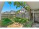 A sunny backyard with overgrown grass, a partial fence, and neighboring houses at 102 S College Ave, Kenly, NC 27542