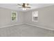 Bright bedroom featuring two windows, neutral carpet, and a ceiling fan for added comfort at 102 S College Ave, Kenly, NC 27542