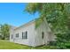 Side of house showing white siding, green shutters, and mature trees at 102 S College Ave, Kenly, NC 27542