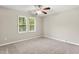 A neutral carpeted bedroom with two windows and a ceiling fan at 102 Winged Foot Ct, Mebane, NC 27302