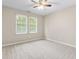 A neutral carpeted bedroom with two windows and a ceiling fan at 102 Winged Foot Ct, Mebane, NC 27302