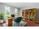 Bright home office featuring a wooden desk, teal office chair, and a custom built-in bookshelf at 102 Winged Foot Ct, Mebane, NC 27302