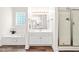 Bright bathroom boasts a tub, walk-in shower, and white vanity, complete with modern fixtures and wood-look flooring at 1033 Cabin Hill Way, Garner, NC 27529