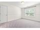 A bright empty bedroom has neutral walls and carpet, with a window view of the trees at 1033 Cabin Hill Way, Garner, NC 27529