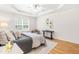 Bright main bedroom featuring a large window, hardwood floors, and a tray ceiling at 1033 Cabin Hill Way, Garner, NC 27529