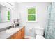 Clean bathroom with wooden vanity, framed mirror, and natural light at 114 Bonaparte Dr, Hillsborough, NC 27278