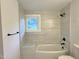 Bathroom with a tub and shower, marble tile, black fixtures and natural light at 114 N Guthrie Ave, Durham, NC 27703