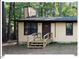 Tan cabin with front door, steps and small deck surrounded by tall trees at 125 Forsyth Dr, Chapel Hill, NC 27517
