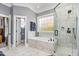 Bright bathroom features tiled shower, soaking tub and window at 12500 Richmond Run Dr, Raleigh, NC 27614