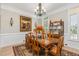 Formal dining room featuring a chandelier, wainscoting, wooden furniture, and natural light at 12500 Richmond Run Dr, Raleigh, NC 27614