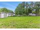 A huge grassy backyard with a partial view of the home with lush greenery and trees at 128 W Parker St, Henderson, NC 27536