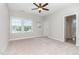 Well-lit bedroom with carpeted floors, a ceiling fan, and two windows showing the outside foliage at 1304 Revolution Cir, Raleigh, NC 27603