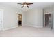 A spacious bedroom with carpeted floors, featuring a ceiling fan and a view of the ensuite bathroom at 1304 Revolution Cir, Raleigh, NC 27603