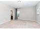 A spacious bedroom with neutral carpet and an ensuite bathroom featuring a window and grey curtain at 1304 Revolution Cir, Raleigh, NC 27603