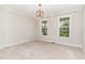 A simple bedroom with neutral walls and carpet, with a simple light fixture and two windows at 1304 Revolution Cir, Raleigh, NC 27603