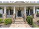 Inviting front porch with stone pillars, hanging plants, and a decorative black door at 1304 Revolution Cir, Raleigh, NC 27603