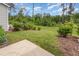 Lush backyard with vibrant greenery, featuring a well-maintained lawn, mature shrubs, and a concrete patio for outdoor enjoyment at 136 Ashlar Ct, Cary, NC 27519