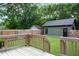 Large backyard featuring a wooden deck, a privacy fence, green lawn, and mature trees at 1405 Watts St, Durham, NC 27701
