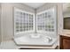 Bright bathroom featuring a soaking tub with privacy glass block windows and stone countertops at 1420 Lagerfeld Way, Wake Forest, NC 27587