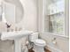 Stylish powder room featuring a pedestal sink, natural light, and a decorative mirror at 192 Glenpark Pl, Cary, NC 27511