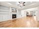 Open concept living room with hardwood floors, fireplace, and built-in shelving; kitchen view in background at 192 Glenpark Pl, Cary, NC 27511
