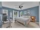 Comfortable blue bedroom featuring natural light from the windows, a ceiling fan and minimalist décor at 201 Crossfire Rd, Holly Springs, NC 27540