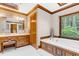 Bright bathroom features a soaking tub, wooden cabinets, and natural light from the window at 201 Village Dr, Knightdale, NC 27545