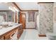 Bright bathroom with a wood vanity, complemented by classic floral wallpaper and white tile flooring at 201 Village Dr, Knightdale, NC 27545