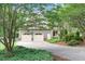 Detached two-car garage with a spacious driveway surrounded by lush greenery and trees at 201 Village Dr, Knightdale, NC 27545