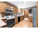Kitchen with white countertops, black appliances, and wood cabinets and flooring at 201 Village Dr, Knightdale, NC 27545