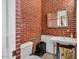 Small, red brick walled bathroom features an artistic mirror, a toilet, and a small sink at 202 Hilltop Ave, Garner, NC 27529
