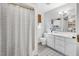 A full bathroom featuring a tub and shower, white vanity, and bamboo shade at 202 Hilltop Ave, Garner, NC 27529