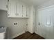 Well-lit laundry room featuring white cabinets, wood-look flooring, and a convenient utility sink at 2032 Sherry Lynn Dr, Garner, NC 27529