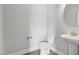 Modern powder room with pedestal sink, round mirror, and white toilet against light grey walls and hardwood floors at 209 Broomgrove Way, Wake Forest, NC 27587
