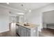 Kitchen island with sink and stainless dishwasher overlooks an open-concept floor plan with light grey walls and hardwood floors at 209 Broomgrove Way, Wake Forest, NC 27587