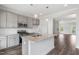 Modern kitchen features stainless appliances, grey cabinets, granite counters, an island, and an open-concept floor plan at 209 Broomgrove Way, Wake Forest, NC 27587
