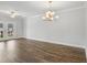 Bright, open living room features hardwood floors and a modern chandelier with doors to the outside at 209 Broomgrove Way, Wake Forest, NC 27587