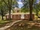 Charming two-story home with brick and yellow siding and red shutters, nestled among mature trees at 223 Shadowbrook Dr, Burlington, NC 27215