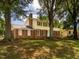 Charming two-story home with brick and yellow siding and red shutters, nestled among mature trees at 223 Shadowbrook Dr, Burlington, NC 27215