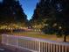 Beautiful backyard with string lights, mature trees, and a pool in the distance at 3208 Wilbon Ridge Dr, Holly Springs, NC 27540
