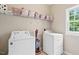 Laundry room features modern appliances, a window, and overhead shelving for storage at 3208 Wilbon Ridge Dr, Holly Springs, NC 27540