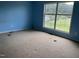 Bedroom with blue walls, stained carpeting, and a large window with an exterior view at 3213 Sam Usry Rd, Oxford, NC 27565