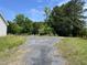 A long paved driveway leads into a wooded area on a partially overgrown lot with an unkempt landscape at 3213 Sam Usry Rd, Oxford, NC 27565