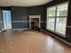 A living room with a fireplace shows signs of needed repairs, with laminate flooring and a large window at 3213 Sam Usry Rd, Oxford, NC 27565