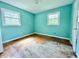 Bedroom with damaged wood floors, blue walls, and window letting in natural light at 3716 Rivermont Rd, Durham, NC 27712