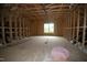 Unfinished attic showcasing the wooden framework, window, and insulation, revealing potential for customization and expansion at 4109 Stonewall Dr, Raleigh, NC 27604